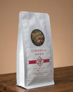 Coffee bag labeled 'Ethereal Dawn' from 'Fabled Roast' on a wooden surface with a beige background